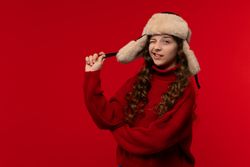 Playful girl in a red sweater and fur hat winks