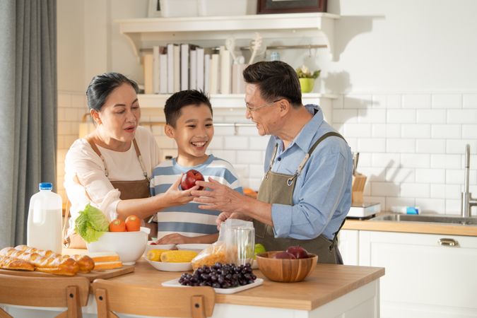 Asian grandparents support and help grandson cooking breakfast in the kitchen