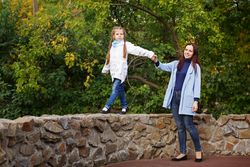 Woman helping female child balance on wall