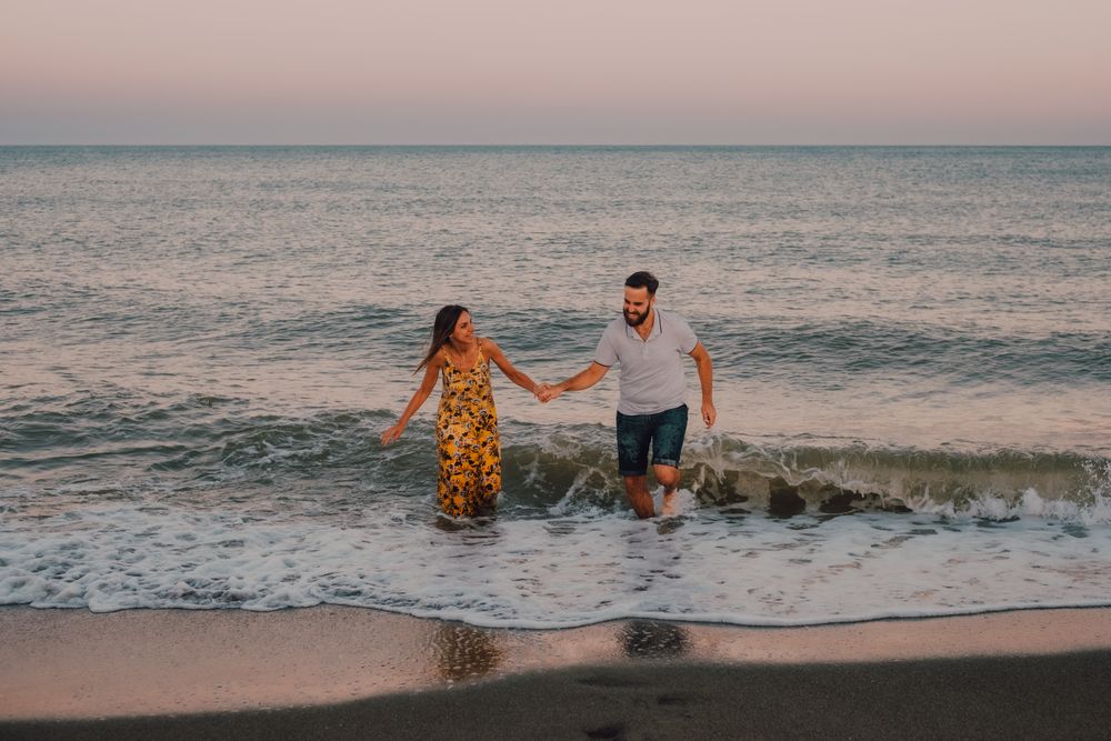 Lovely couple running holding hands on sandy beach