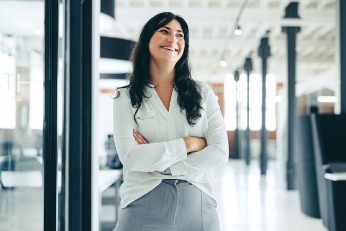 Cheerful businesswoman standing with her arms crossed