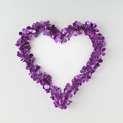 Purple confetti shaped in heart outline on light background