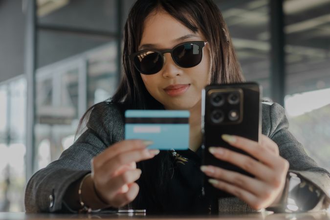 Woman using a smartphone and credit card for online transactions
