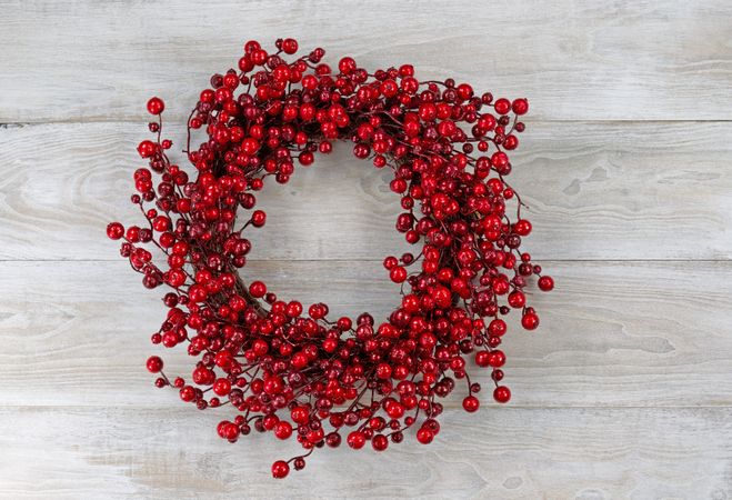 Red berry holiday wreath on rustic wooden boards