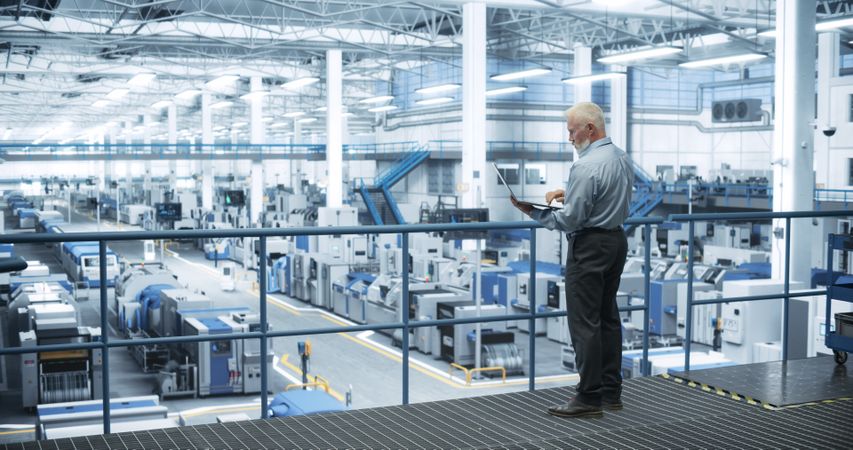 Thoughtful Engineer Monitoring and Analyzing Conditions at a Pristine Modern Electronics Factory with Automated Mobility Robots Working with the Help of Artificial Intelligence Software
