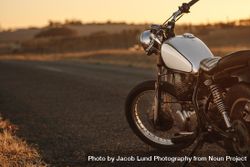 Vintage motorcycle parked on empty rural road at sunset 5wPqy4