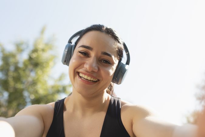 A young woman takes a selfie while listening music and practice sports in a park in the morning, Zaragoza, Spain