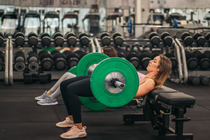 two young fitness women training hip thrust in a gym