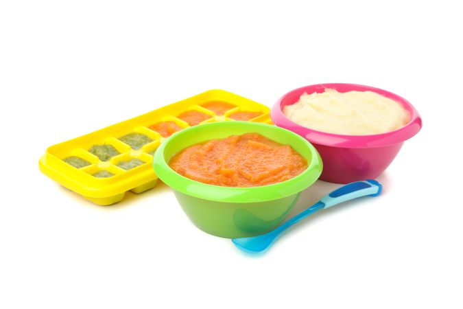 Bowls with vegetable puree on plain background. Baby food