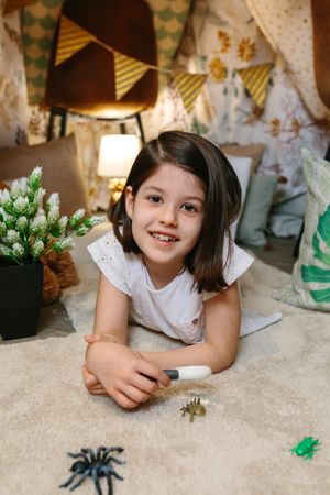 Girl playing with magnifying glass and toy bugs