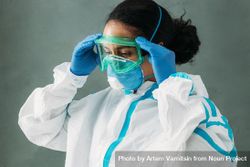 Side view of Black female medical professional in PPE gear adjusting her googles 0K6xVb