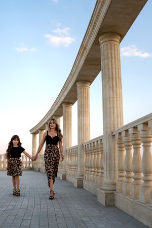 Mom and little daughter walk around city in evening