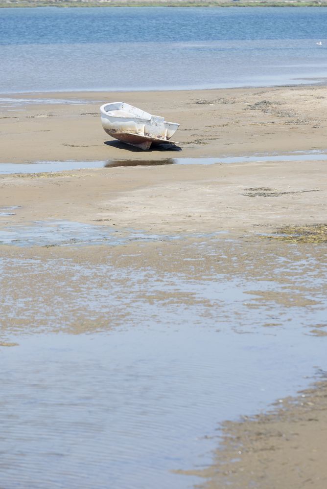 Old rowing boat on sandy wet beach