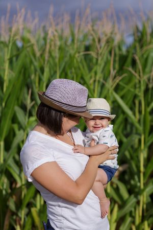 Adorable mother and child on hand enjoying and laughing in field