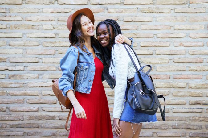 Two women hugging in front of a brick wall