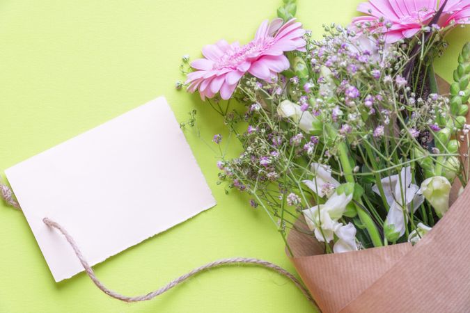 Bouquet of flowers with a blank message card on green background