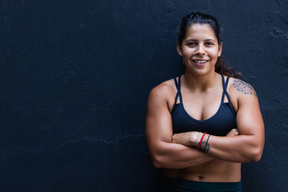 Hispanic sportswoman standing near wall