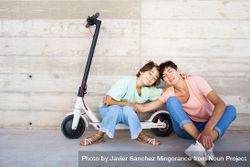 Woman and preteen girl sitting on the ground outside posing with a scooter 5k7GQ5