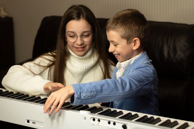 Young boy and teen girl playing the piano together.