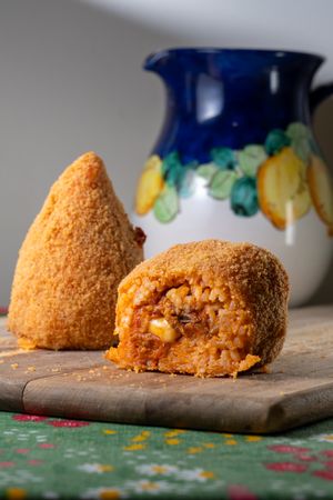 Sicilian arancino with ceramic jug and colorful tablecloth