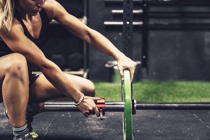 Concentrated female fixing barbell before workout