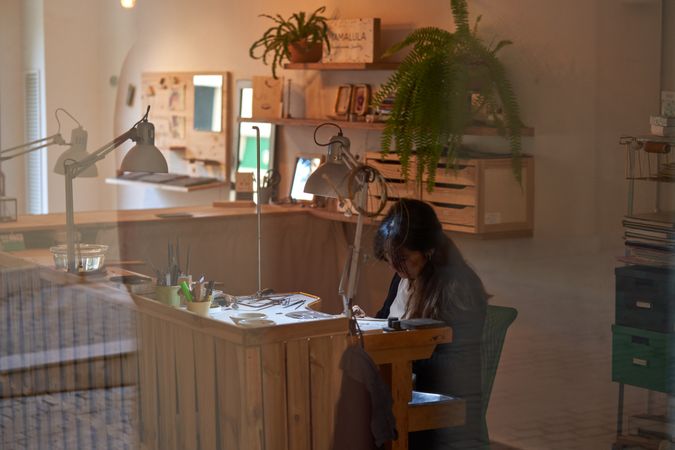 Professional female jeweler working at wooden bench