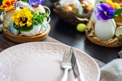 Easter holiday table setting with close up of decorative eggs with colorful flowers around a pink plate