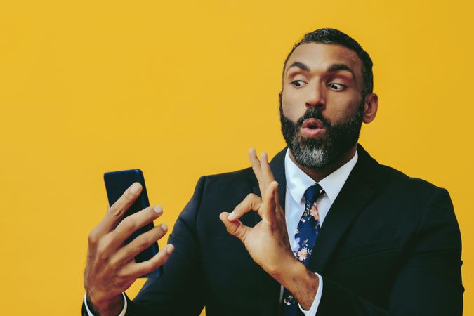 Cautious Black businessman in suit gesturing at smartphone screen