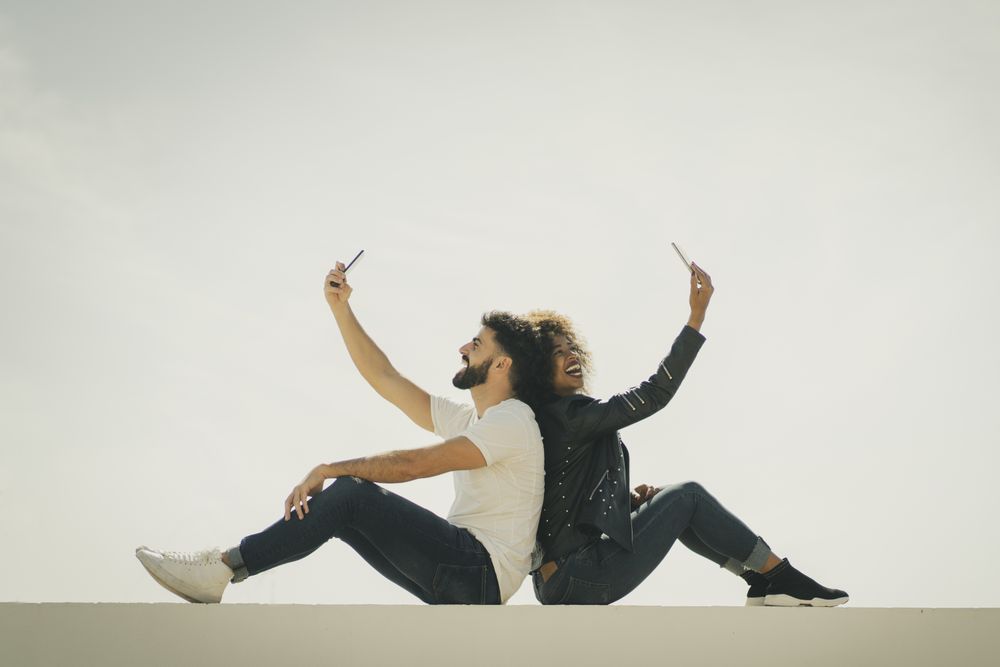 Happy couple taking selfies on wall