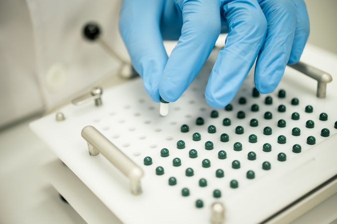 Crop compounding pharmacist putting pill into capsule filler