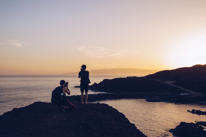 Travelers taking photo on seaside at sunset