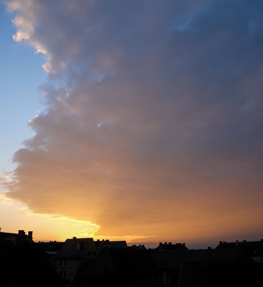 Orange and blue sky at sunset over French rooftops