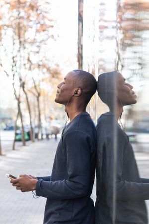 Black man listening to music in earphones on smartphone