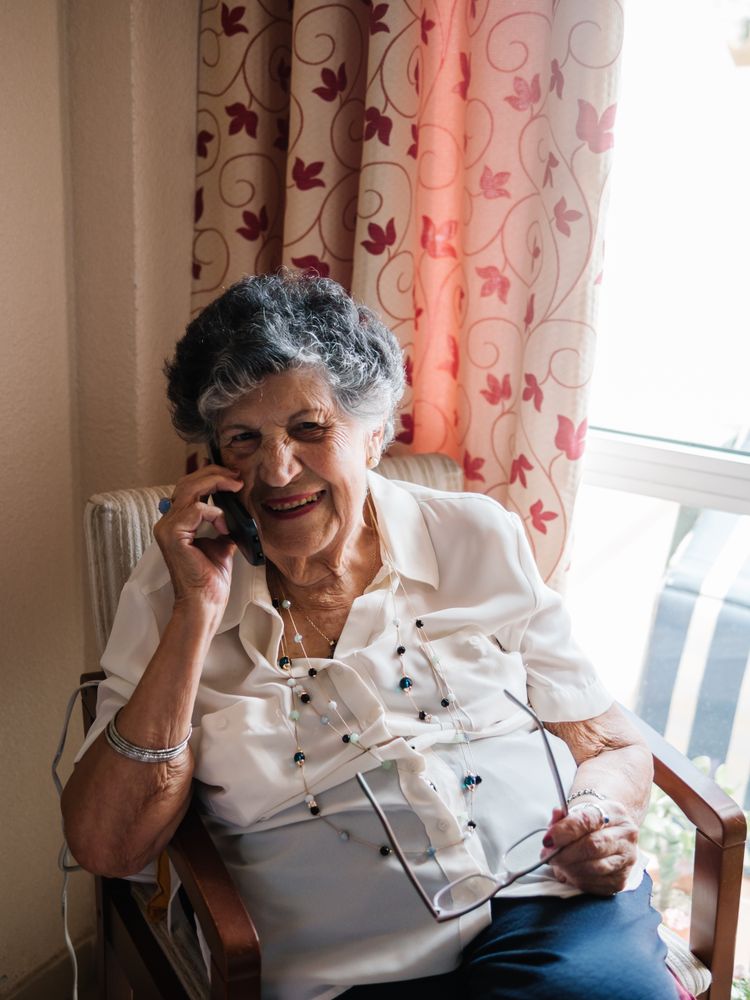 Cheerful mature woman talking on cell phone at home