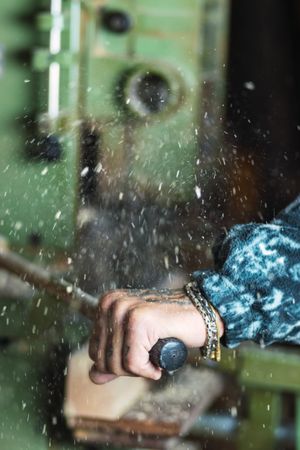 Crop anonymous woodworker sawing planks in workshop