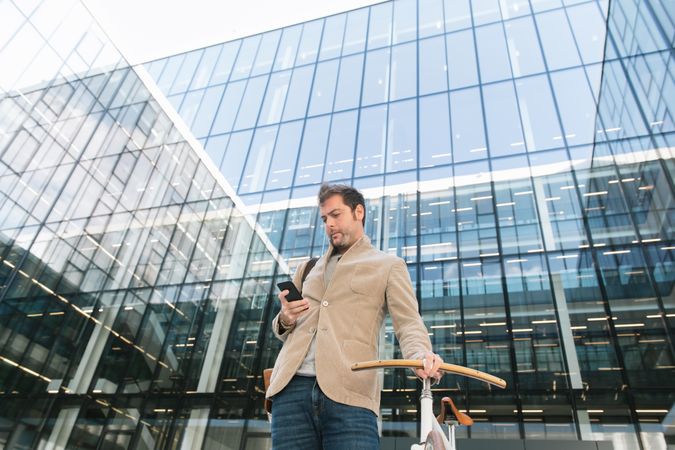 Man phoning while standing against modern building in downtown