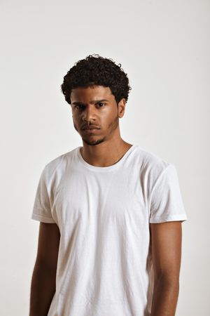 Portrait of Black man with curly hair and plain t-shirt with pensive look on his face