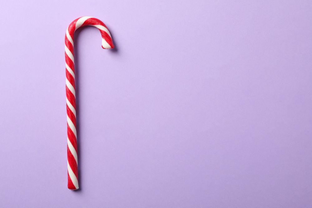Sweet candy cane on color background, space for text