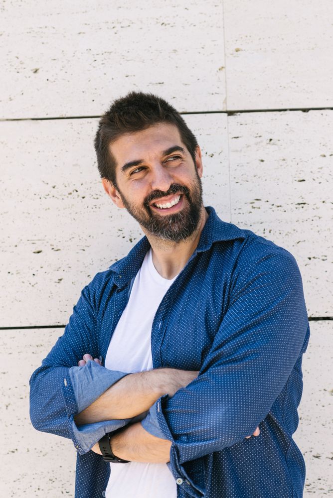 Smiling confident man in denim standing outside with arms crossed