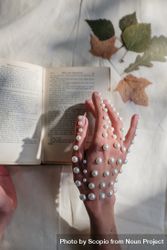 Cropped image of hand with pearls turning a page 5QXnd0