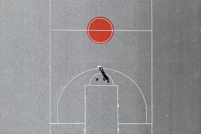 A man playing hoops on a minimal basketball field