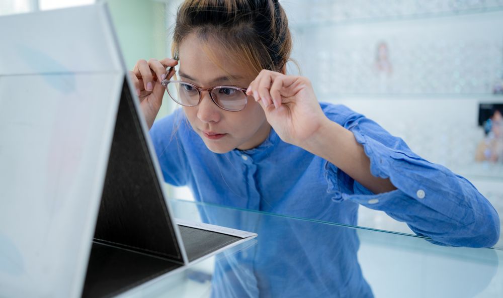 Female tried on the glasses and looked in the mirror.