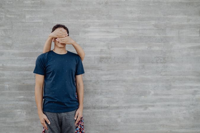 Woman closing eyes of man by hands leaning on wall