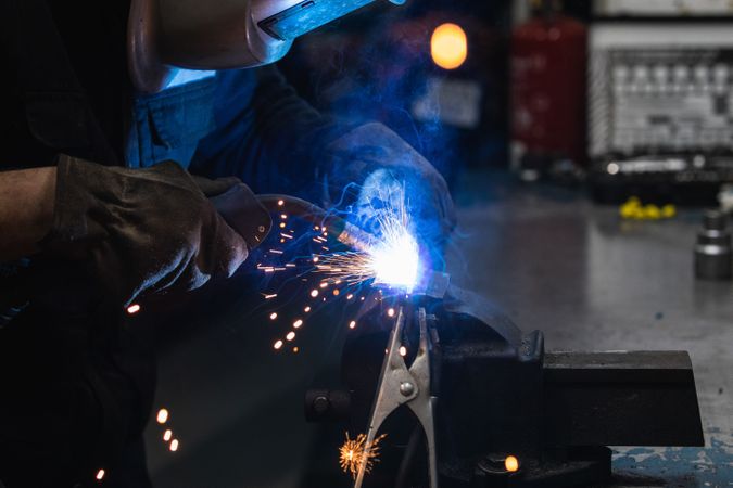 Anonymous mechanic welding metal construction in workshop