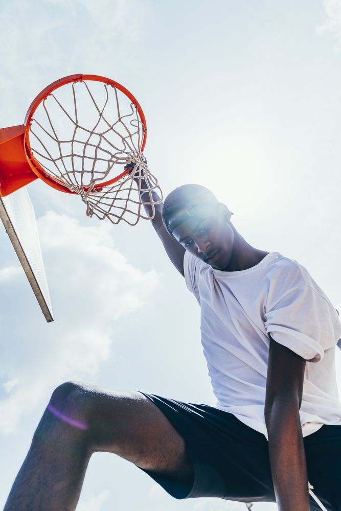 Black sportsman hanging on basketball lap