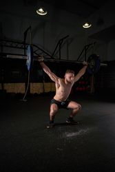 Strong sportsman doing weightlifting exercise with barbell