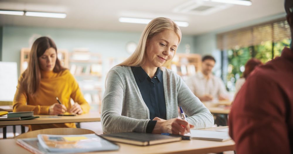 Diverse Mature Students Learning in Classroom, Reading Textbooks and Writing in Notebooks