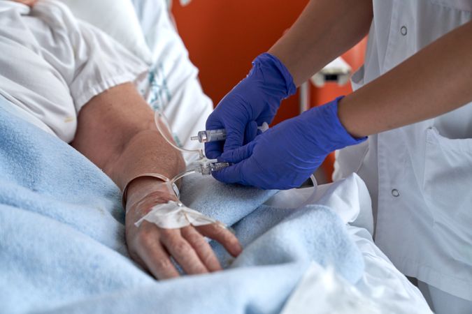 Unrecognizable nurse making injection in catheter of patient