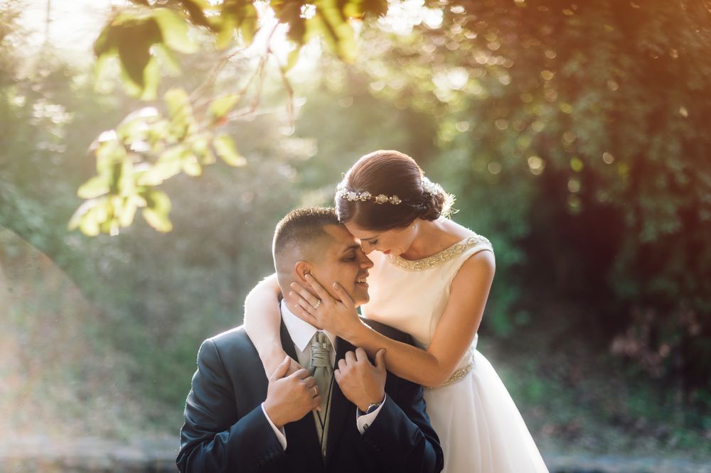 Smiling groom and bride hugging and kissing in park