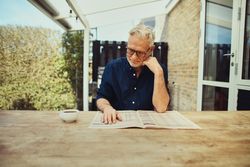Mature man sitting outside reading the paper